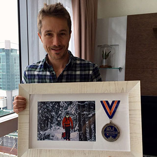 De Decker, at home in Singapore showing off his medal and photo from his race in 2018.